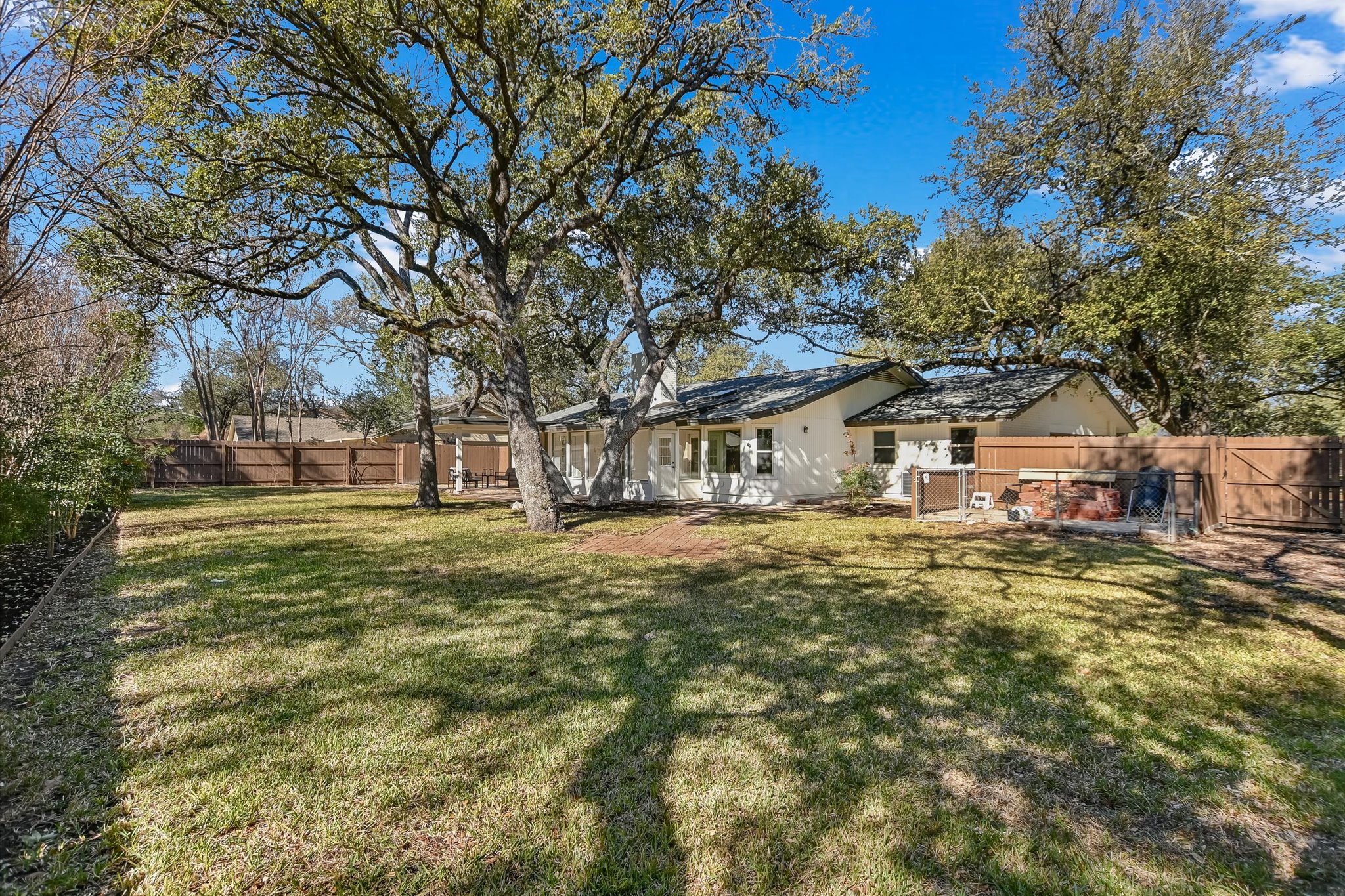 9905 Richelieu Road Austin, TX 78750 - Photo 22 of 32 Back of house with a fenced backyard and compost area for gardening.