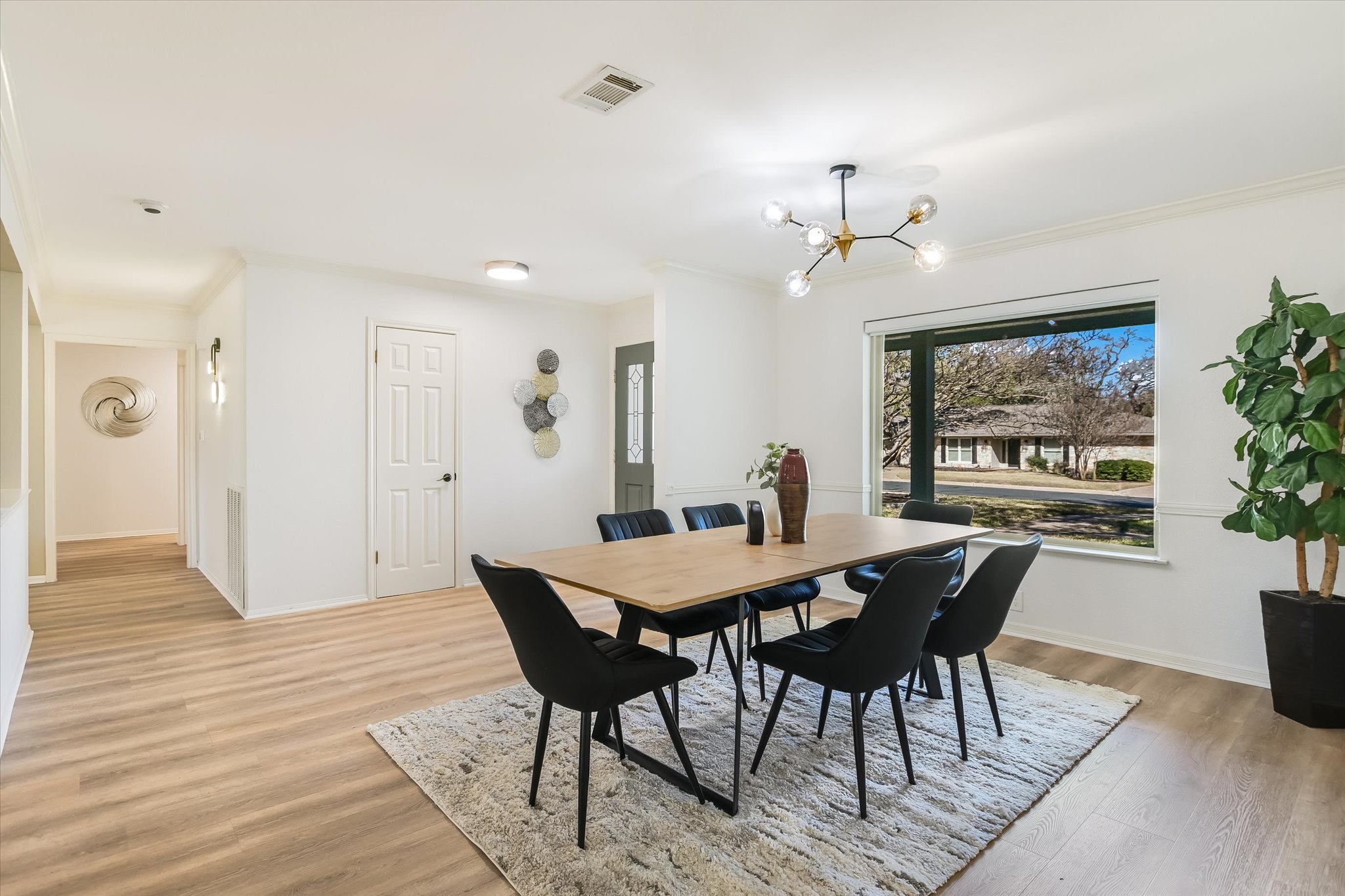 9905 Richelieu Road Austin, TX 78750 - Photo 7 of 32 Dining area featuring light wood look laminate floors, crown molding, and a chandelier