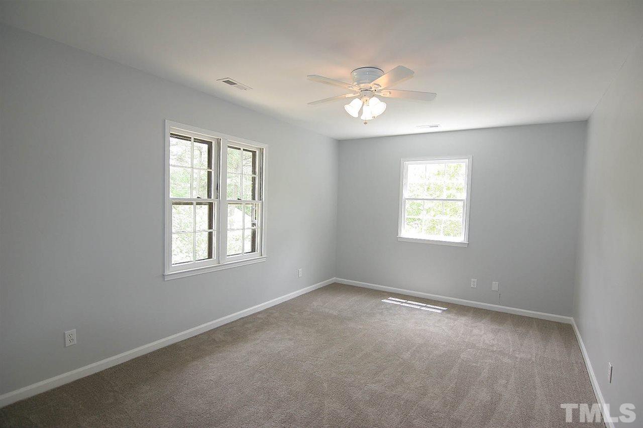 7801 Audubon Drive Raleigh, NC 27615 - Photo 20 of 25 an empty room with windows and chandelier fan