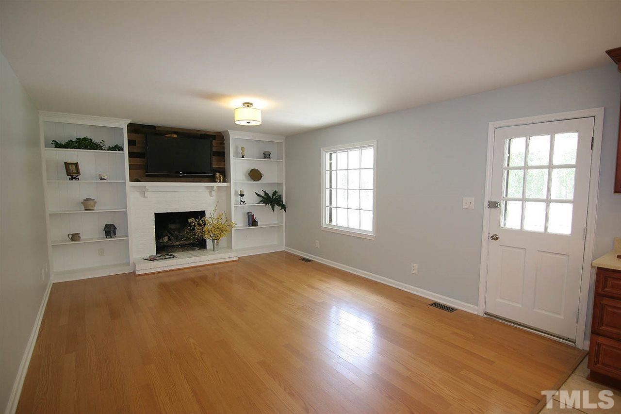 7801 Audubon Drive Raleigh, NC 27615 - Photo 7 of 25 an empty room with windows a fireplace and a flat screen tv