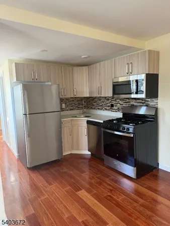a kitchen with a stove top oven a refrigerator a sink and dishwasher with wooden floor