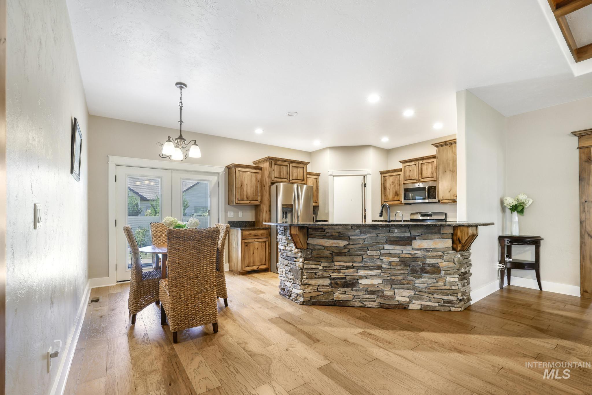 2157 Cayuse Street Twin Falls, ID 83301 - Photo 16 of 48 Kitchen with light wood finished floors, brown cabinetry, a peninsula, a chandelier, and pendant lighting