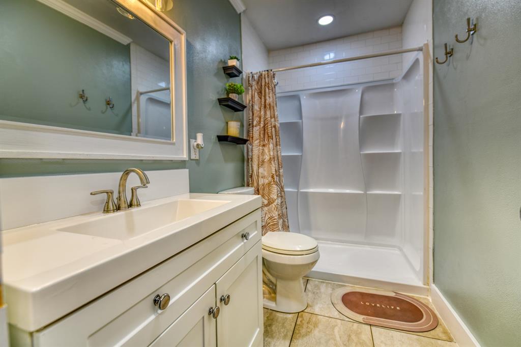 3214 Parker Street Irving, TX 75062 - Photo 14 of 22 a bathroom with a sink a toilet and a mirror