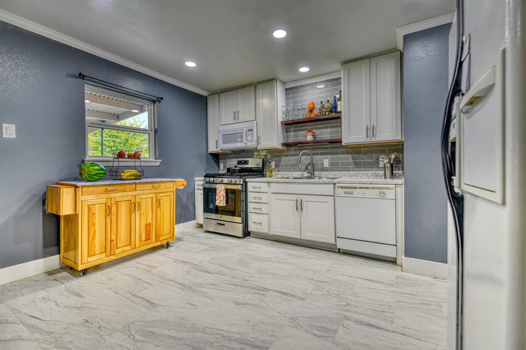 3214 Parker Street Irving, TX 75062 - Photo 10 of 22 a kitchen with stainless steel appliances granite countertop a stove a sink and a refrigerator with cabinets