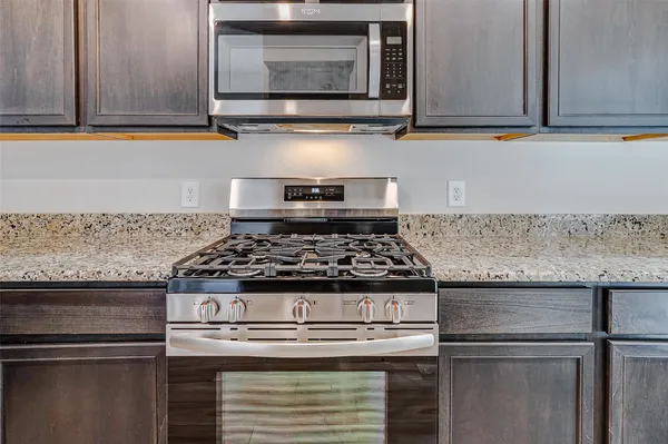 a kitchen with granite countertop a stove and a microwave