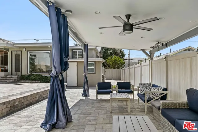 a patio table and chairs with potted plants on wooden floor