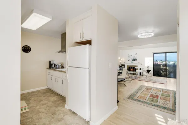 a view of a kitchen with white cabinets and refrigerator