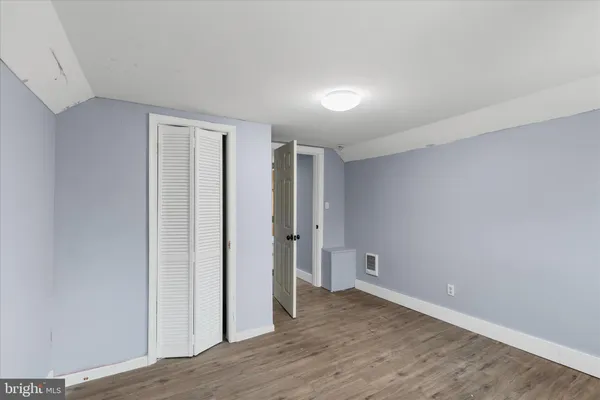 a view of an empty room with wooden floor and closet