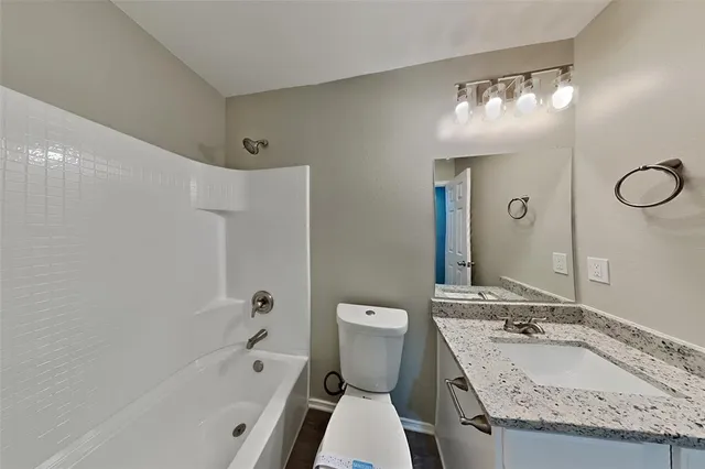 a bathroom with a granite countertop sink a toilet a mirror and bathtub