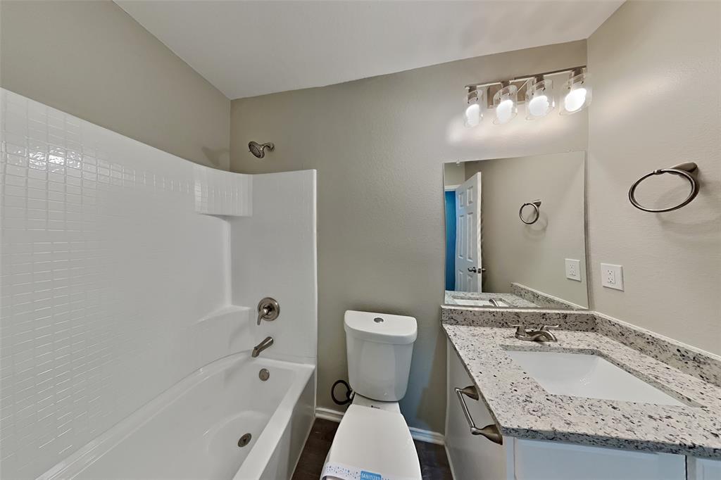 5804 Mirror Ridge Drive Fort Worth, TX 76179 - Photo 16 of 19 a bathroom with a granite countertop sink a toilet a mirror and bathtub