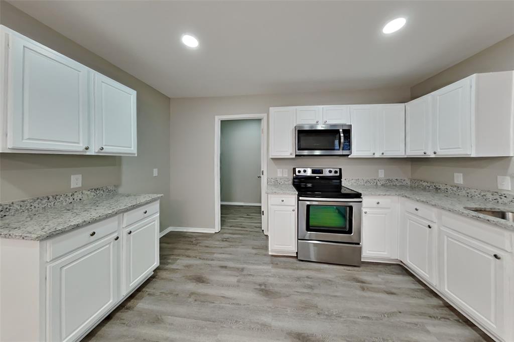 5804 Mirror Ridge Drive Fort Worth, TX 76179 - Photo 5 of 19 a kitchen with granite countertop a stove top oven a sink a counter space and cabinets