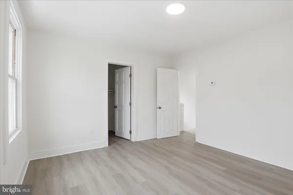 a view of an empty room with wooden floor and closet
