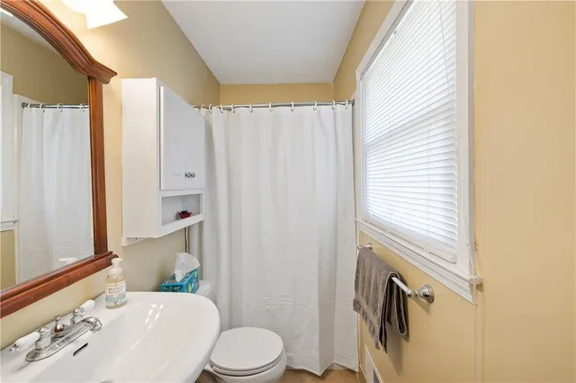 a bathroom with a sink a toilet and shower curtain