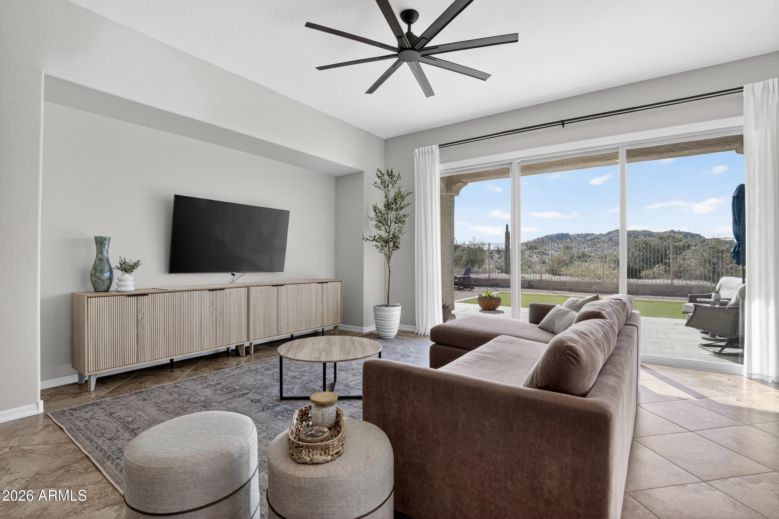 18377 Verdin Road Goodyear, AZ 85338 - Photo 6 of 55 a living room with furniture a flat screen tv and a floor to ceiling window