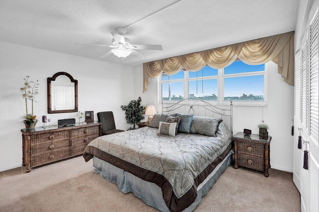 303 North Riverside Drive, Unit 503 Pompano Beach, FL 33062 - Photo 11 of 29 a bedroom with a large bed and a chandelier