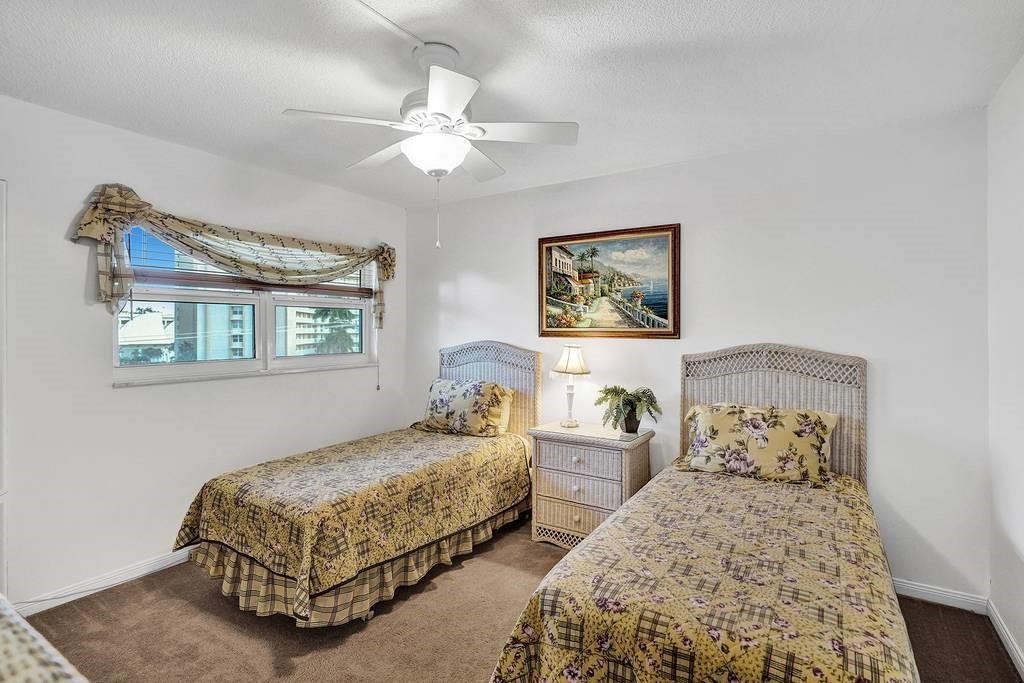 303 North Riverside Drive, Unit 503 Pompano Beach, FL 33062 - Photo 16 of 29 a bedroom with two beds and a chandelier