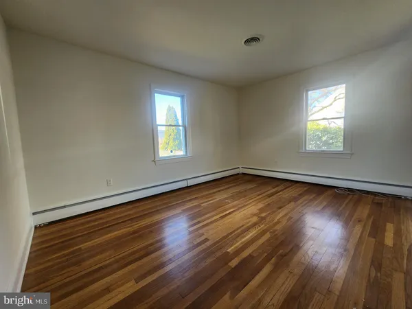 an empty room with wooden floor fireplace and windows