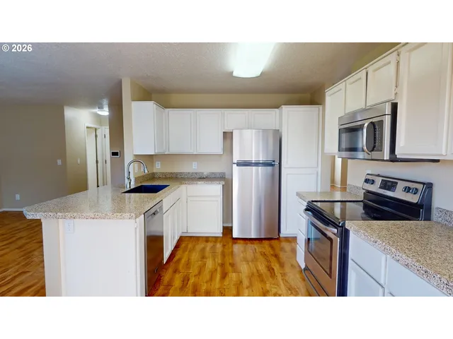 a kitchen with kitchen island a counter top space a sink stainless steel appliances and cabinets