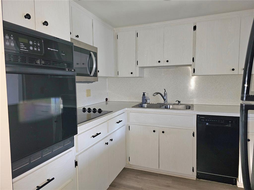 2457 Ecuadorian Way, Unit 75 Clearwater, FL 33763 - Photo 3 of 62 a kitchen with granite countertop white cabinets and black appliances