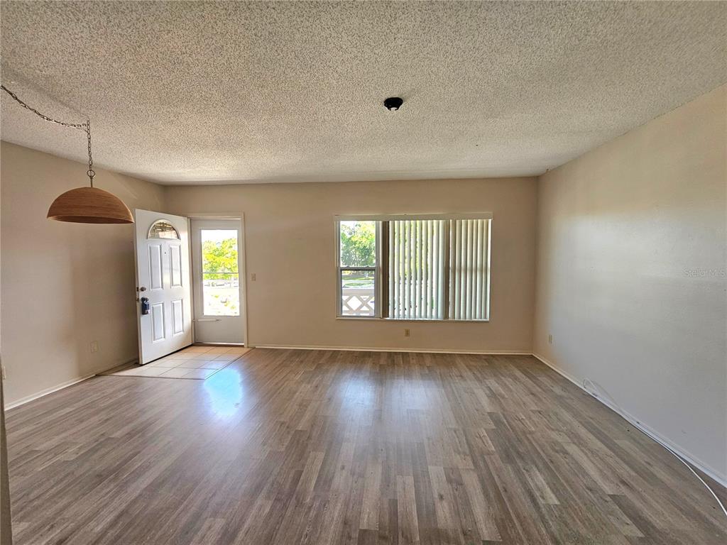 2457 Ecuadorian Way, Unit 75 Clearwater, FL 33763 - Photo 5 of 62 an empty room with wooden floor and windows