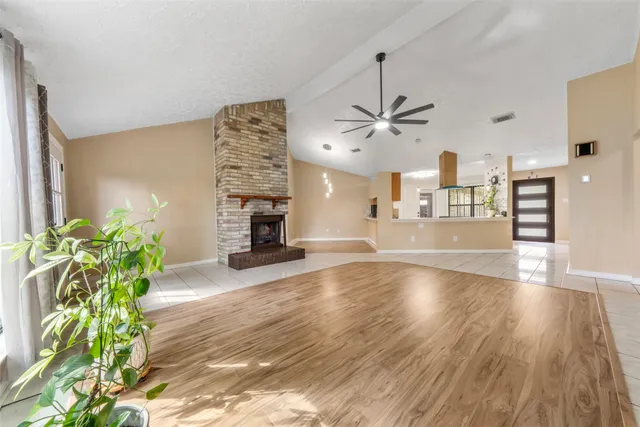a view of an empty room and a kitchen with wooden floor