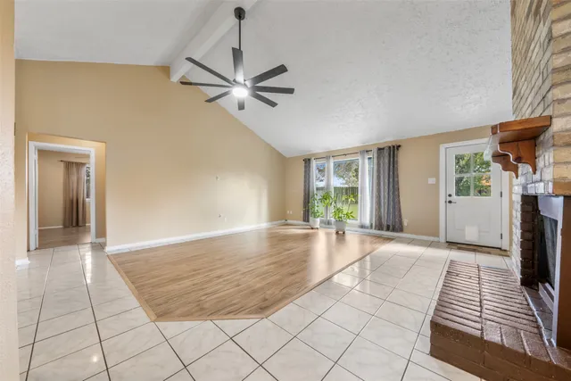 a view of an empty room with window and chandelier fan
