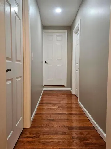 a view of an empty room with wooden floor and closet