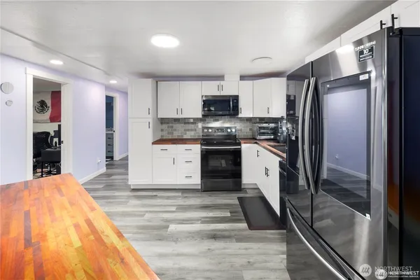 a large kitchen with stainless steel appliances kitchen island granite countertop a refrigerator and a stove top oven