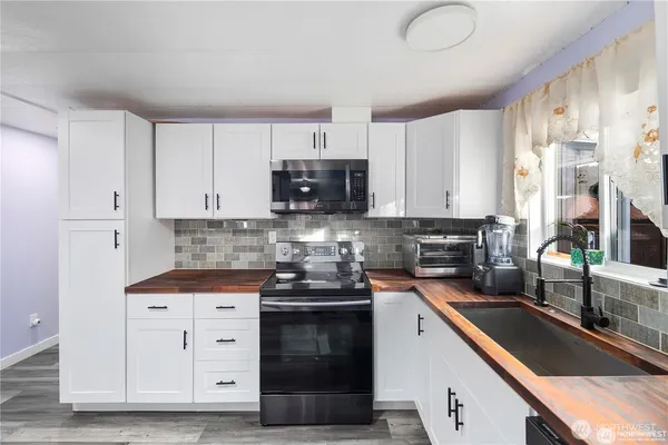 a kitchen with stainless steel appliances granite countertop a sink a stove and a microwave