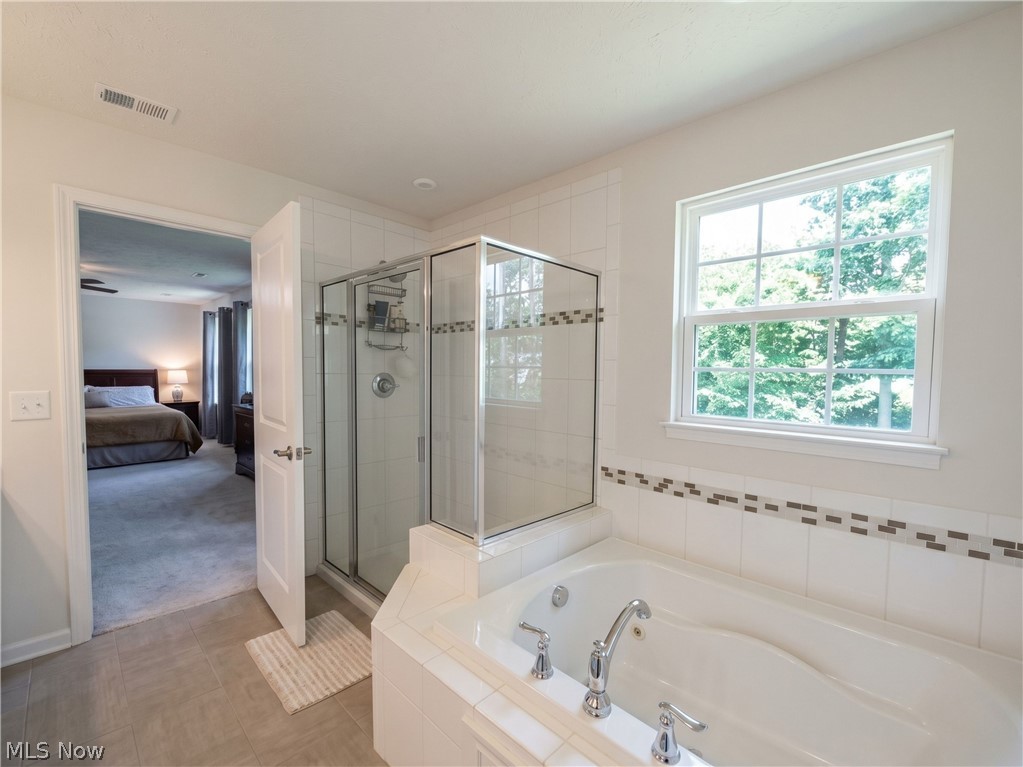 4509 Millbrook Way Akron, OH 44321 - Photo 20 of 27 Bathroom featuring a jetted soaking tub, tiled shower with glass enclosure, single window, and neutral tile flooring