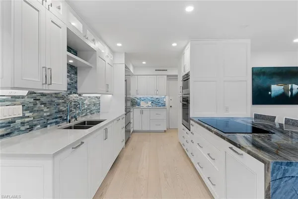 a large kitchen with kitchen island granite countertop a sink and white cabinets