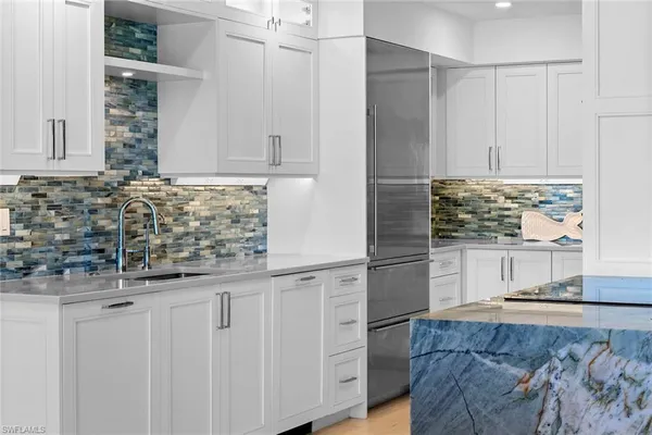 a kitchen with white cabinets and sink