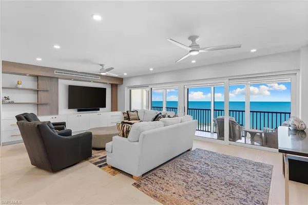 a living room with furniture floor to ceiling window and a flat screen tv