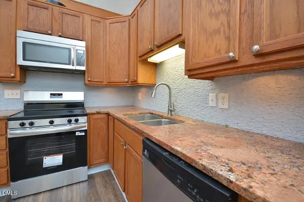 a kitchen with stainless steel appliances granite countertop wooden cabinets a sink and dishwasher