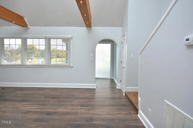 a view of a hallway with wooden floor and a bathroom