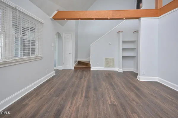 a view of a hallway with wooden floor and a bathroom