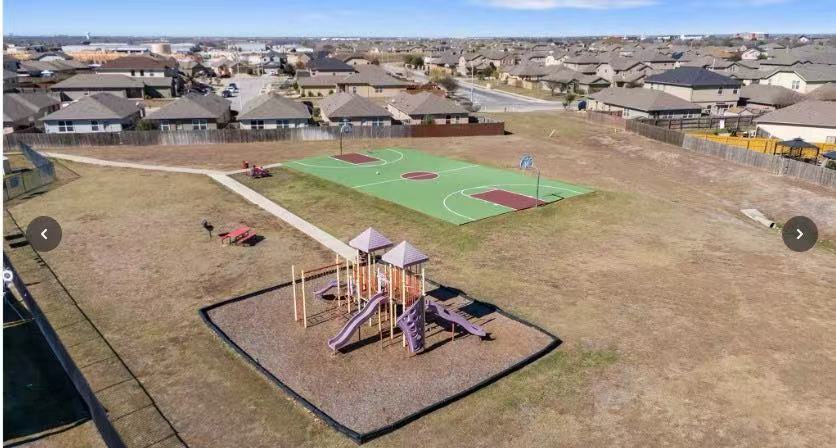 14917 Bajada Rd Manor Manor, TX 78653 - Photo 30 of 31 Outdoor recreation area featuring a basketball court, playground equipment, paved walking paths, and open green space