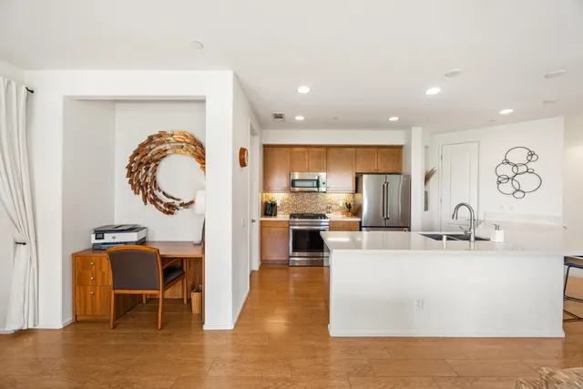 a living room with stainless steel appliances furniture a rug and a kitchen view