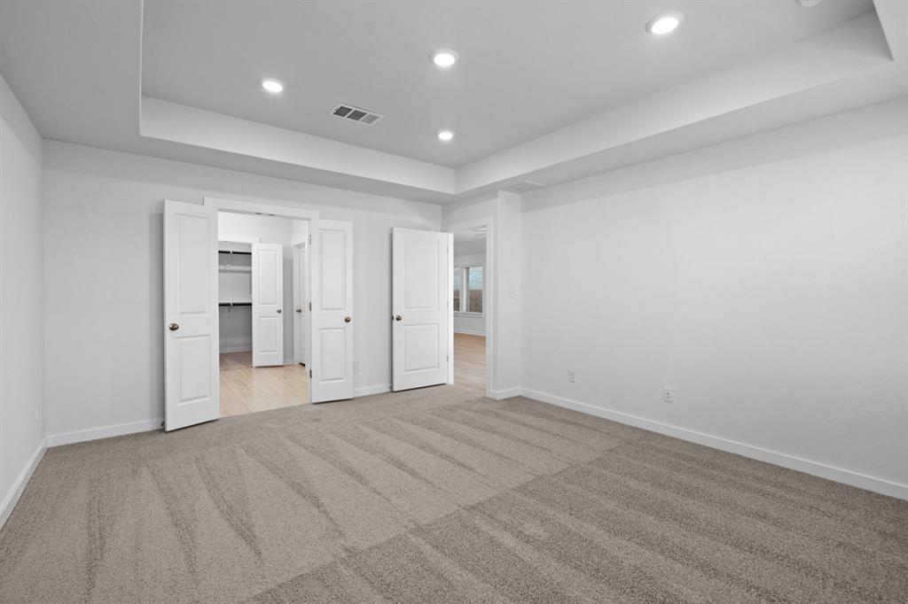 212 Brandywine Road Hutto, TX 78634 - Photo 9 of 35 Unfurnished bedroom with a raised ceiling, recessed lighting, light colored carpet, and a walk in closet