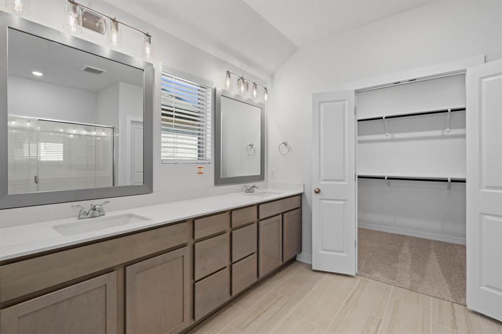 212 Brandywine Road Hutto, TX 78634 - Photo 11 of 35 Full bathroom featuring double vanity, a stall shower, vaulted ceiling, and a walk in closet
