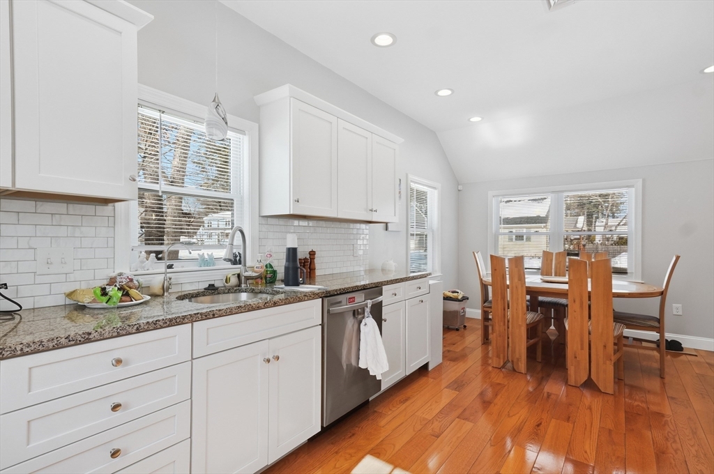 24 Holly Street Billerica, MA 01821 - Photo 9 of 33 a kitchen with granite countertop white cabinets a sink a stove a dining table and chairs