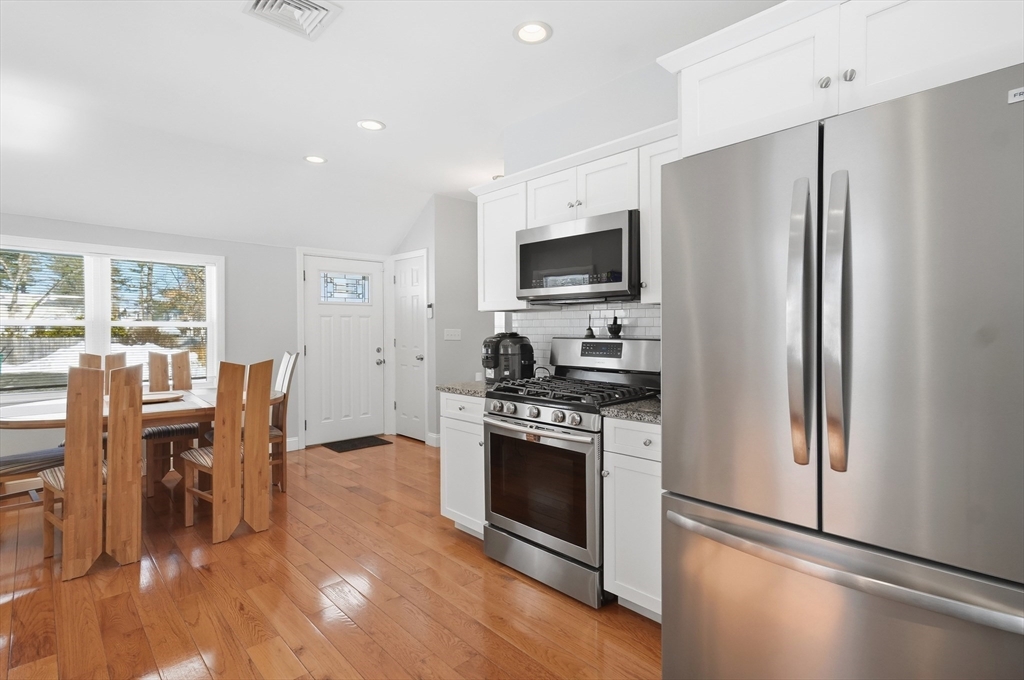 24 Holly Street Billerica, MA 01821 - Photo 10 of 33 a kitchen with stainless steel appliances a stove a sink refrigerator and a dining table with wooden floor