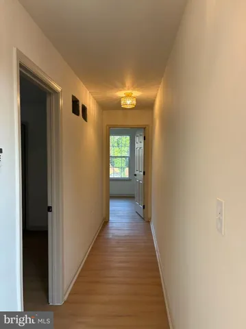 a view of a hallway with wooden floor and a living room