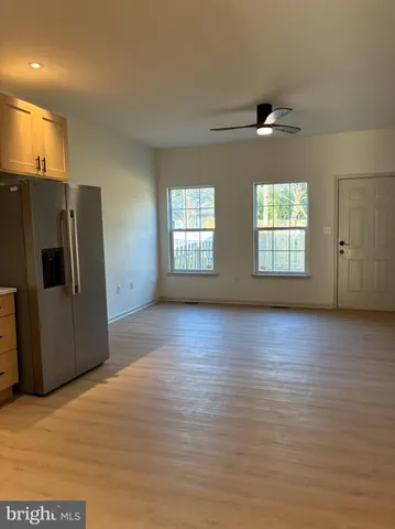 a view of an empty room with a kitchen and a window