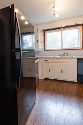 a kitchen with stainless steel appliances granite countertop a refrigerator a sink and a stove with wooden floor