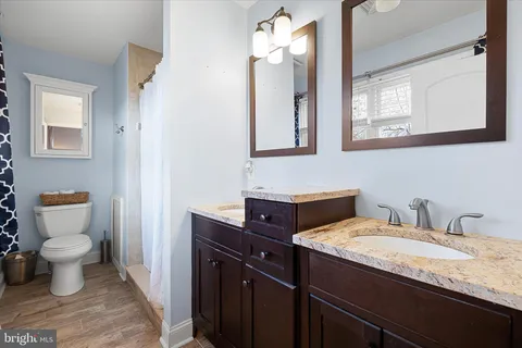 a bathroom with a granite countertop toilet sink and mirror