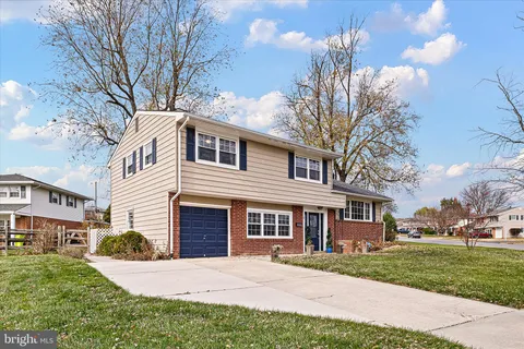 a front view of a house with a garden and trees