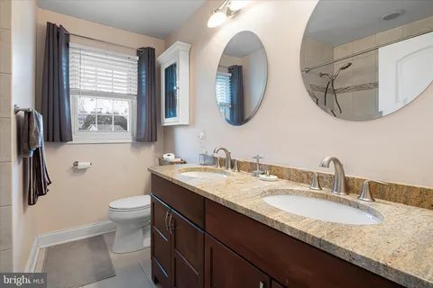 a bathroom with a granite countertop sink a toilet and a mirror
