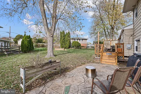 a view of a backyard with table and chairs couches fire pit and large trees