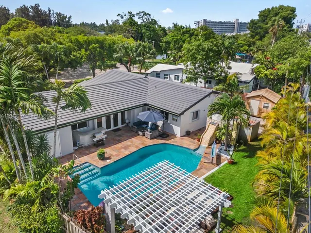 an aerial view of a house with swimming pool and next to a yard